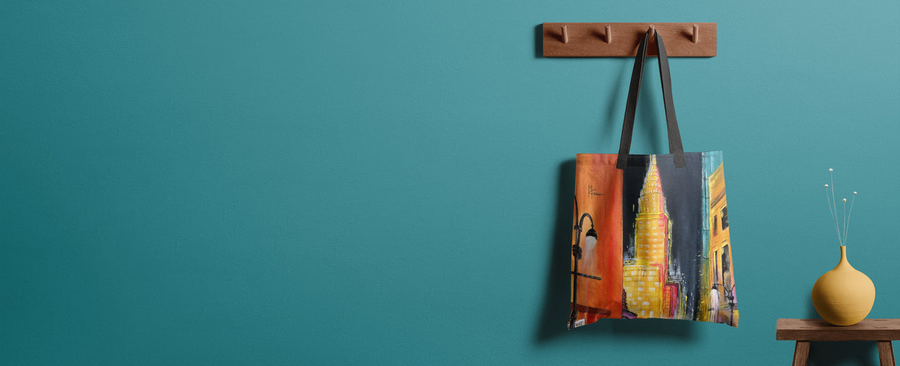 Colorful tote bag with cityscape design hanging on a wooden hook against a teal wall.
